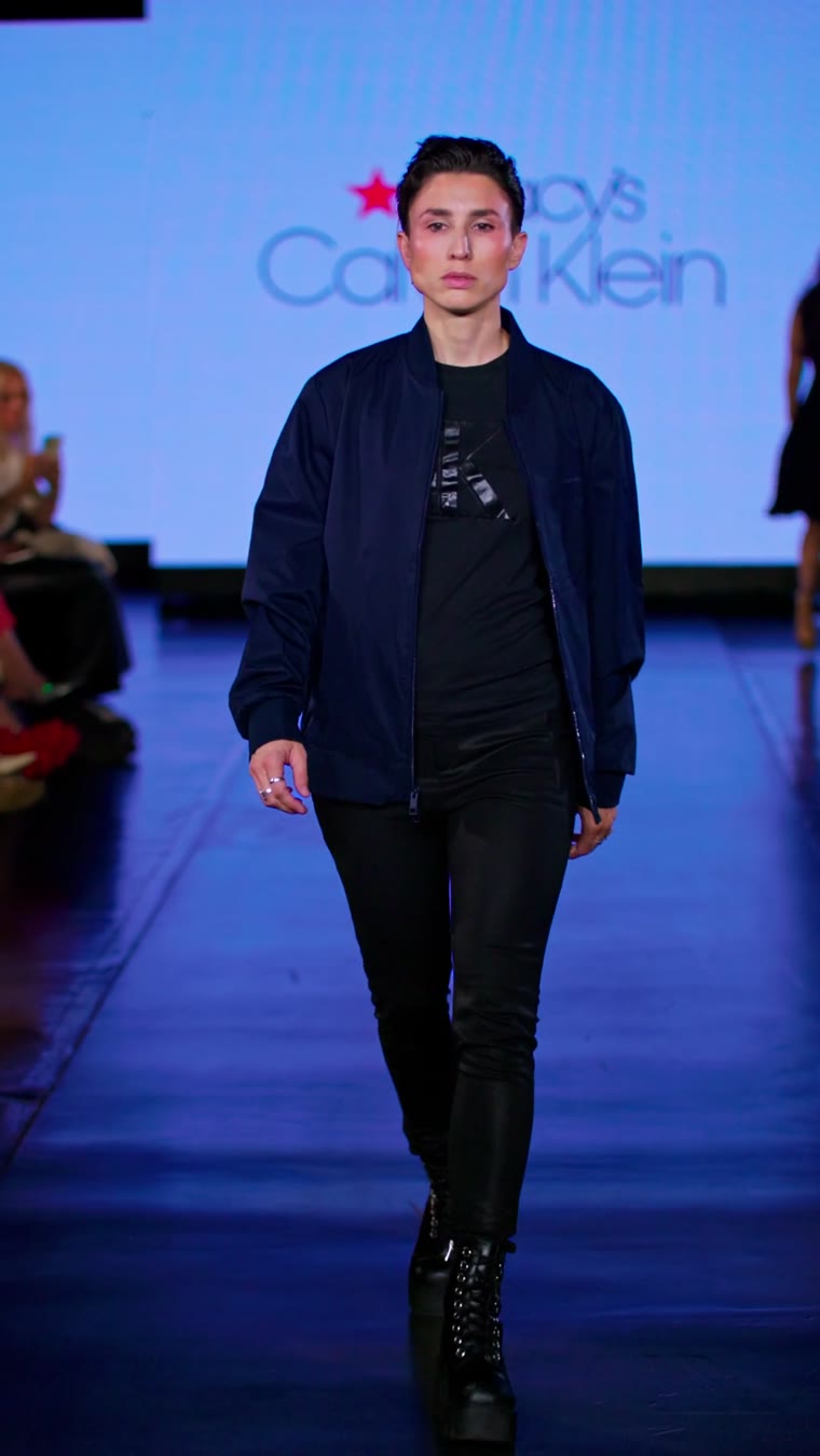 A model in a navy bomber jacket walking the runway