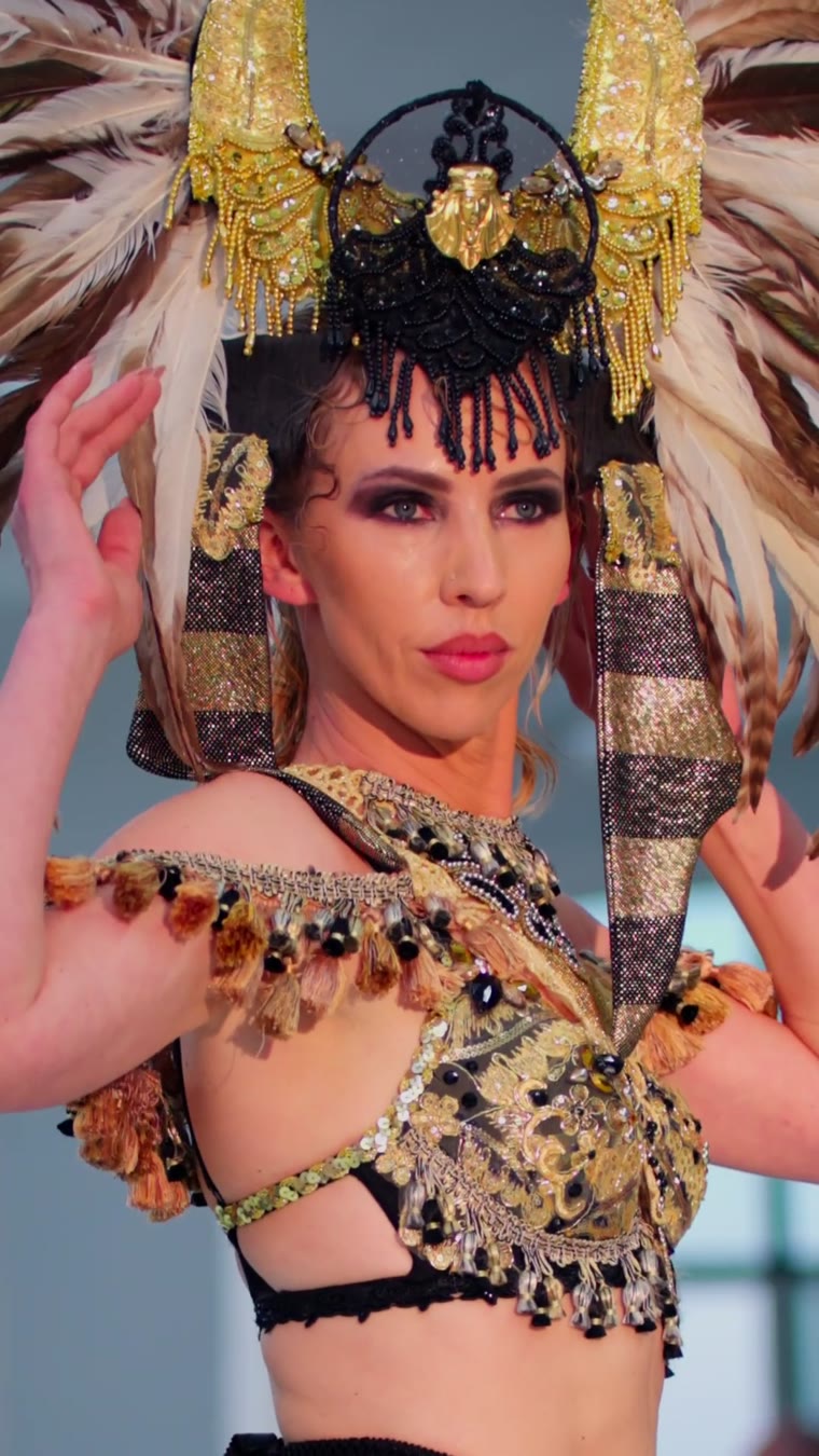 A model in a gold Egyptian headdress and gold top on the runway