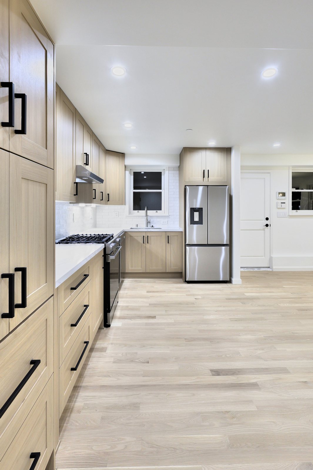 Remodeled kitchen with light oak cabinets and a stainless fridge
